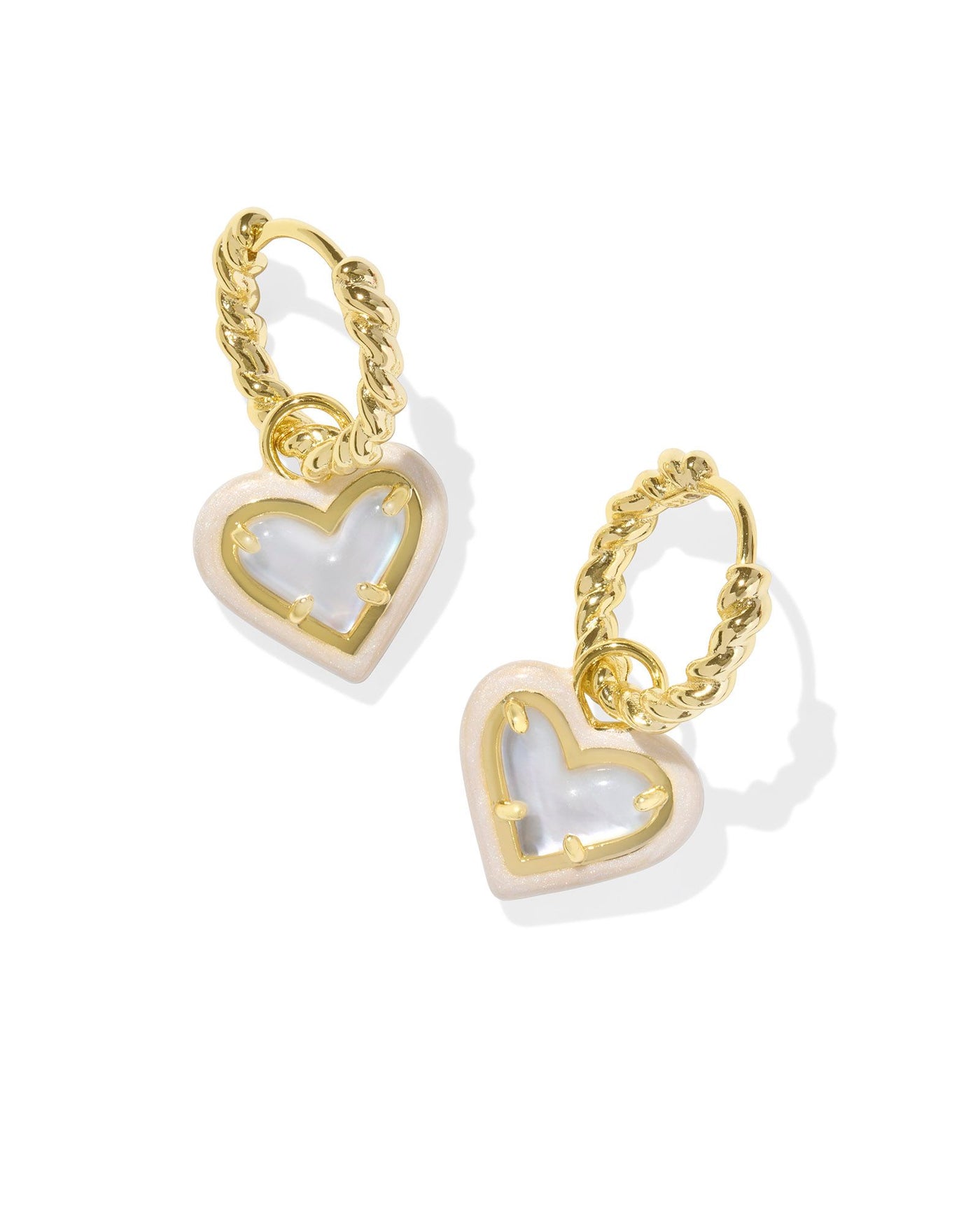 Twisted gold huggie hoops with enamel framed ivory mother of pearl heart pendant.