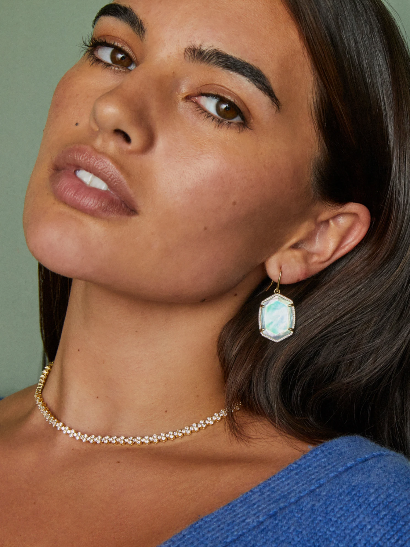 Gold earrings with pave framed iridescent ivory mother of pearl hexagon pendant on model, front view.